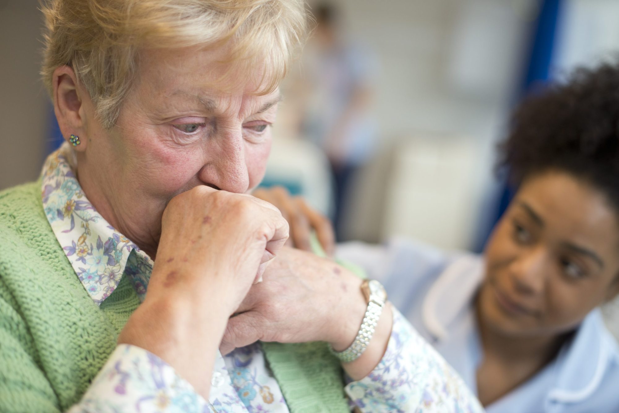 Nurse comforting distressed elderly woman
