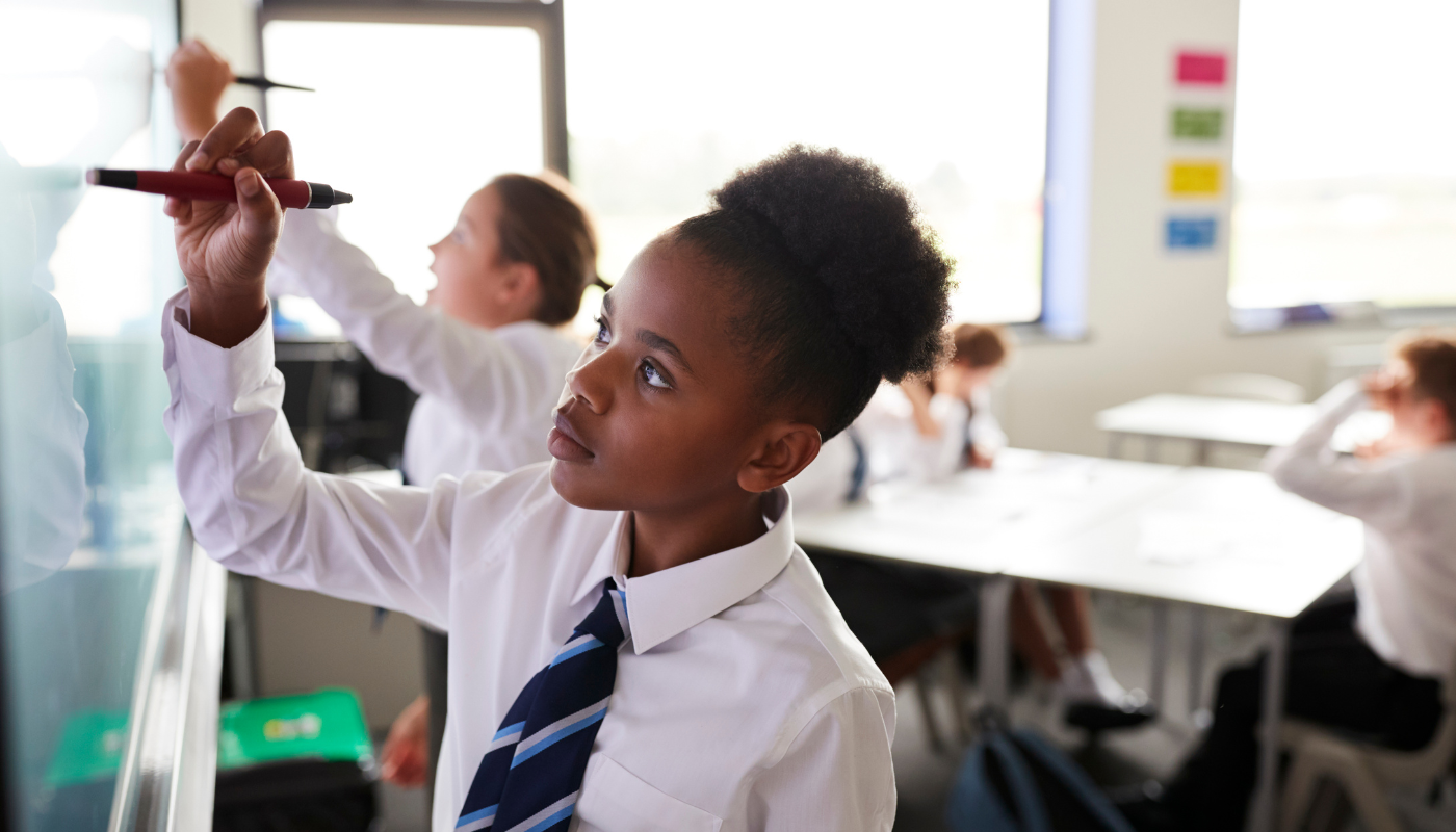 Schoolgirl in uniform writing on a whiteboard
