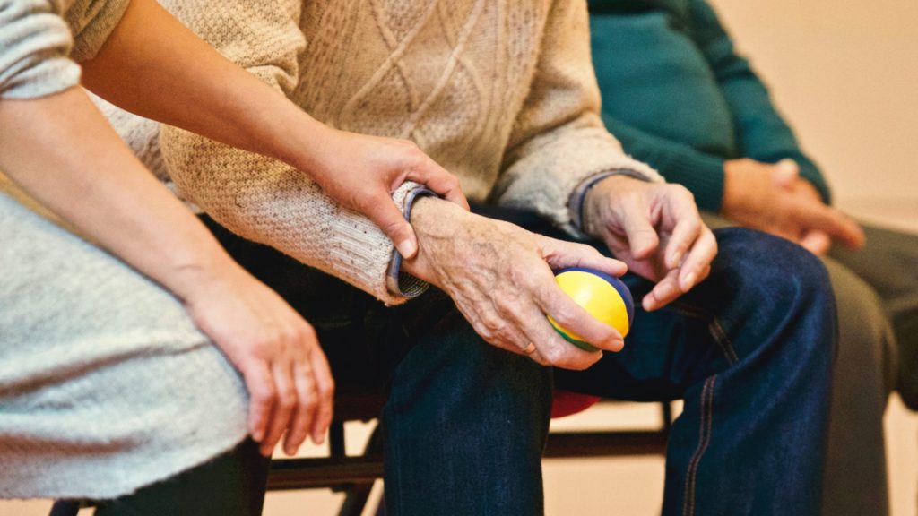 Elderly male in care home setting holding stress ball